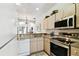 Functional kitchen layout featuring stainless steel appliances, light wood cabinets, and a view of the dining area at 1180 S Beach Cir, Kissimmee, FL 34746