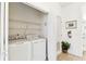 Bright laundry room features a stacked washer and dryer unit, wire shelving for storage, and convenient access to the home at 1180 S Beach Cir, Kissimmee, FL 34746