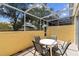 Outdoor patio features seating for four and screened enclosure, providing a comfortable and shaded spot to enjoy the backyard at 1180 S Beach Cir, Kissimmee, FL 34746