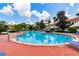 Beautiful community pool with lounge chairs, lush landscaping, and a bright blue sky at 1180 S Beach Cir, Kissimmee, FL 34746