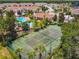 Aerial view of a tennis court nestled in a community surrounded by lush trees and townhomes at 1180 S Beach Cir, Kissimmee, FL 34746
