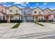 Exterior view of a row of colorful townhouses featuring red tile roofs and landscaped front yards at 1180 S Beach Cir, Kissimmee, FL 34746
