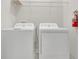 Bright laundry room features a modern washer and dryer with overhead shelving and a fire extinguisher for added safety at 12307 Turtle Grass Dr, Orlando, FL 32824