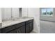 Stylish bathroom with dual granite sinks, modern fixtures, and access to carpeted bedroom at 1247 Blue Daze Ln, Eustis, FL 32726