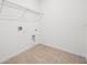 Bright laundry room with tile floor, utility connections, and wire shelving ready for washer and dryer at 1247 Blue Daze Ln, Eustis, FL 32726