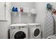Functional laundry room equipped with washer, dryer, shelving, and ironing board at 13437 Granger Ave, Orlando, FL 32827