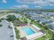 An aerial view features a community pool and common green space bordered by houses and a picturesque lake at 1397 Gatlin Pl, The Villages, FL 32163