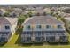 Back exterior of townhome featuring a screened-in porch overlooking a lush green lawn at 17419 Placidity Ave, Clermont, FL 34714