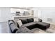 Open-concept living room, kitchen and dining area with sleek white cabinets and an inviting gray sectional sofa at 2005 Noble Dr, Davenport, FL 33837