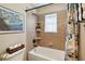 Tiled bathroom with a tub, shower with a blue floral curtain, and a framed print of Van Gogh's 