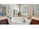 Bright bathroom showcasing a garden tub with tiled surround, plantation shutters, and stylish fixtures at 2116 Truffle Ln, Casselberry, FL 32707