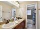 Well-lit bathroom featuring double sinks with bronze fixtures, and a separate room with a tub and tiled walls at 2116 Truffle Ln, Casselberry, FL 32707