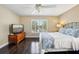 Bedroom with plantation shutters, dark wood floors, ceiling fan, and a television on a rustic wooden chest at 2116 Truffle Ln, Casselberry, FL 32707