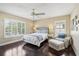 Inviting bedroom with shuttered windows, dark wood floors, a ceiling fan, and a sitting area with a chair and ottoman at 2116 Truffle Ln, Casselberry, FL 32707
