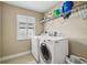 Bright laundry room with white front-load washer and dryer, shelving, and a window with plantation shutters at 2116 Truffle Ln, Casselberry, FL 32707