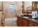 Bathroom features a dark wood cabinet, granite counters and framed mirror, tub, and toilet at 2232 Lake Vilma Dr, Orlando, FL 32835