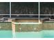 Close up view of the tiled hot tub with waterfall feature flowing into the crystal-clear swimming pool at 2232 Lake Vilma Dr, Orlando, FL 32835