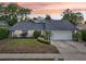 Charming single story home featuring a landscaped front yard, attached two-car garage, and a beautiful sunset sky at 2260 Winslow Cir, Casselberry, FL 32707