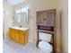 Bright bathroom features a wooden vanity and built-in cabinet, complementing the neutral color scheme at 2369 Haulover Blvd, Deltona, FL 32738