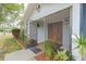 Covered front porch with terracotta tiled flooring, surrounded by landscaped flower beds and a wooden front door at 2369 Haulover Blvd, Deltona, FL 32738