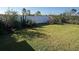 Beautiful backyard with a wide expanse of grass, colorful plants, and a fence for privacy at 2711 Neverland Dr, New Smyrna Beach, FL 32168