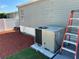 Home exterior featuring modern air conditioning unit, ladder and red mulch for landscape design at 37518 Quail Ridge Cir, Leesburg, FL 34788