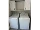 Well-lit laundry room featuring a white washer, dryer, and cabinets for convenient storage at 37518 Quail Ridge Cir, Leesburg, FL 34788