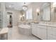 A bright bathroom features a garden tub, double vanity, chandelier, and marble tile flooring at 3883 Grassland Loop, Lake Mary, FL 32746