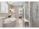 Bright bathroom with marble finishes, a walk-in shower, and a soaking tub with bright natural light at 3883 Grassland Loop, Lake Mary, FL 32746