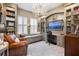 Home office features custom built-ins, large windows, a cozy window seat, and an elegant chandelier at 3883 Grassland Loop, Lake Mary, FL 32746