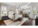 Spacious main bedroom with a stylish canopy bed, dark hardwood floors, and bright natural light at 3883 Grassland Loop, Lake Mary, FL 32746