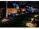 Night view of landscaped backyard with a brick wall, garden lighting, and lush grass at 4793 Grassy Knoll Dr, Tavares, FL 32778