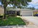 Beautiful single-story home featuring lush green lawn, colorful landscaping, and an attached two-car garage at 4793 Grassy Knoll Dr, Tavares, FL 32778
