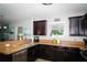 Well-lit kitchen featuring dark wood cabinets, stainless steel dishwasher, and granite countertops at 4793 Grassy Knoll Dr, Tavares, FL 32778