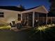 A relaxing screened-in patio with a fire pit table and seating, surrounded by thoughtfully placed landscape lighting at 4793 Grassy Knoll Dr, Tavares, FL 32778