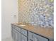 Elegant bathroom vanity features custom cabinetry, stone counters, and beautiful mosaic-tile backsplash at 5525 Isleworth Country Club Dr, Windermere, FL 34786