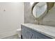Bathroom featuring a gray vanity with marble countertop, oval mirror, and gray tiled walls at 5525 Isleworth Country Club Dr, Windermere, FL 34786