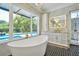 Bathroom with a large freestanding tub and large picture windows with pool views at 5525 Isleworth Country Club Dr, Windermere, FL 34786