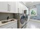 Inviting laundry room featuring modern appliances, white cabinetry, stylish fixtures and wallpaper at 5525 Isleworth Country Club Dr, Windermere, FL 34786