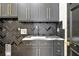 Modern laundry room with dark cabinetry, gold hardware, black herringbone backsplash, and marble countertops at 5525 Isleworth Country Club Dr, Windermere, FL 34786