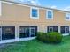 Exterior view of townhome's tan facade, featuring screened patios and privacy hedges at 774 Chelsea Dr, Davenport, FL 33897
