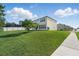 Lush back yard with green lawn, mature tree, and a sidewalk at 1018 Boxelder Ave, Minneola, FL 34715