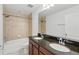 Bathroom with granite countertops, double sinks, and a tiled shower/bath combination at 1018 Boxelder Ave, Minneola, FL 34715