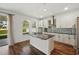 Modern kitchen with granite island, stainless appliances, and views through sunlit windows at 1018 Boxelder Ave, Minneola, FL 34715