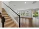 Open living room with wood floors, staircase, and large windows providing natural light at 1018 Boxelder Ave, Minneola, FL 34715