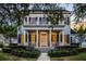 Two-story home featuring a large covered front porch, balcony, manicured landscaping, and warm lighting at 1106 Celebration Ave, Celebration, FL 34747