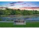 A tranquil lake view with a bench in the foreground, reflecting a beautiful sunset sky with colorful clouds at 1106 Celebration Ave, Celebration, FL 34747