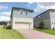 Two-story home with a two-car garage, brick paver driveway, green grass and gray siding at 12272 Bracco St, Winter Garden, FL 34787