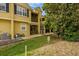 Rear view of a two-story yellow house with a green lawn and mature tree at 1570 Barking Deer Cv, Casselberry, FL 32707