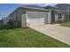 Exterior view of home with green grass, a driveway and white garage door at 1596 Park Side Ave, Kissimmee, FL 34744
